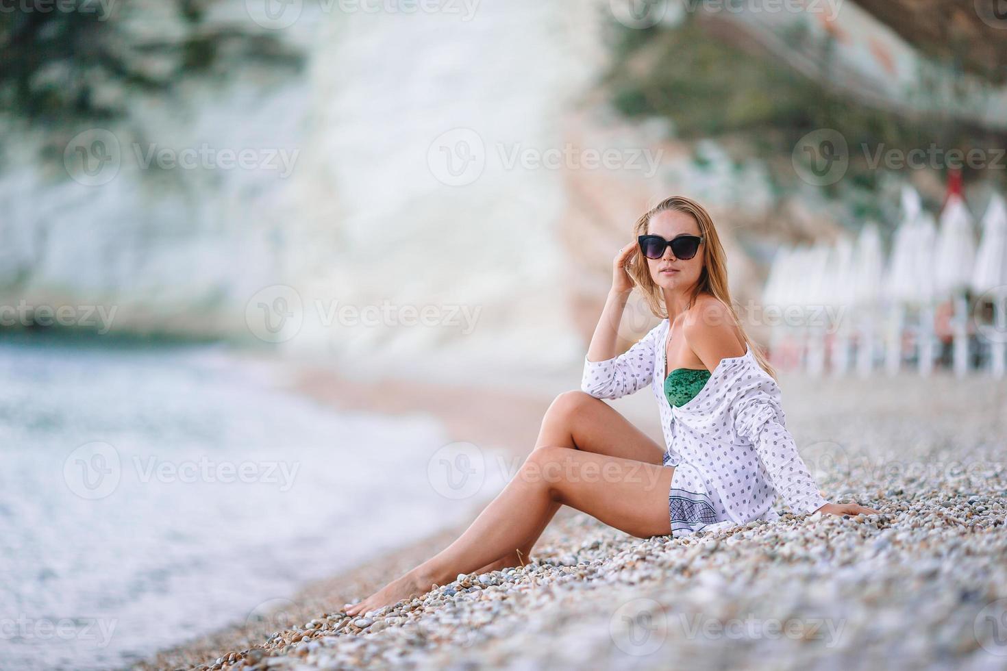 mujer joven disfrutando del sol tomando el sol junto al océano turquesa perfecto foto