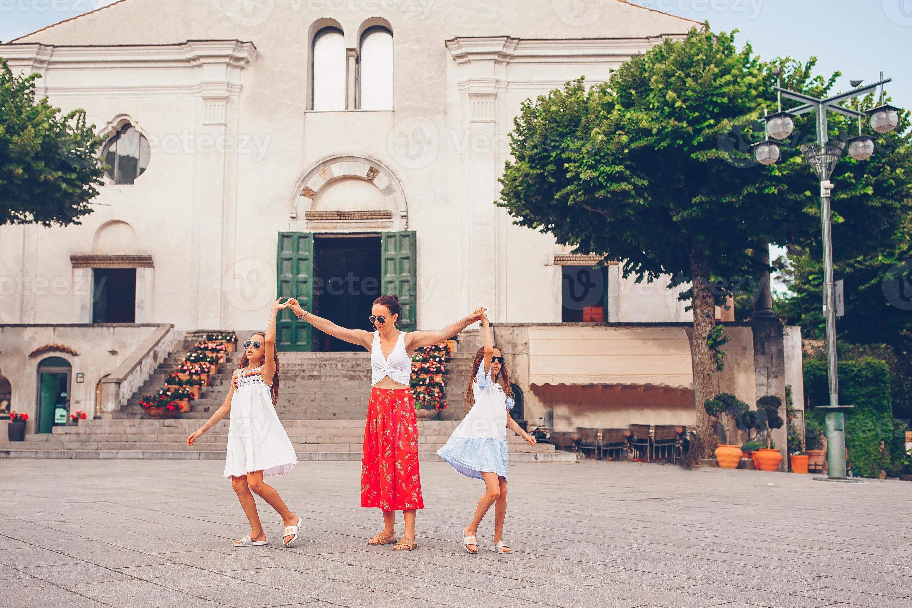 Adorable little girls and young mother have fun in italian old village