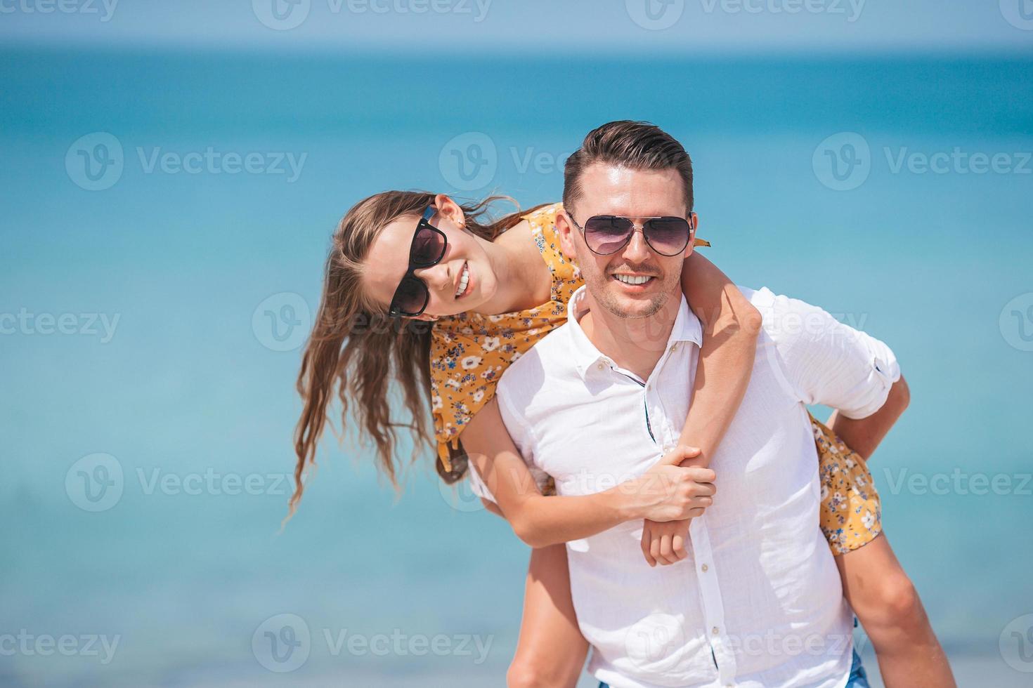 Little girl and happy dad having fun during beach vacation photo
