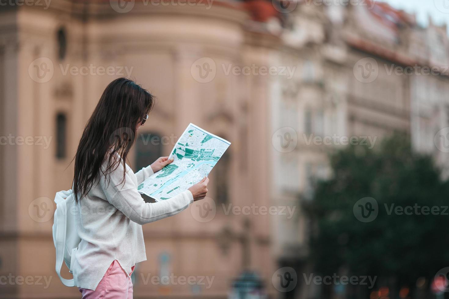 Happy young woman with a city map in city. Travel tourist woman with map in Prague outdoors during holidays in Europe. photo