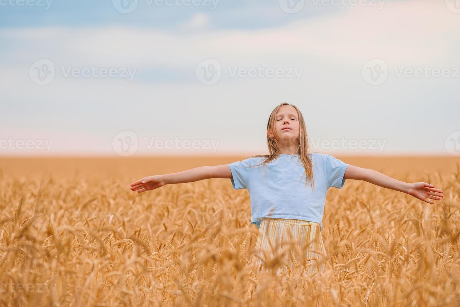 Happy little girl walking in golden fields of wheat photo