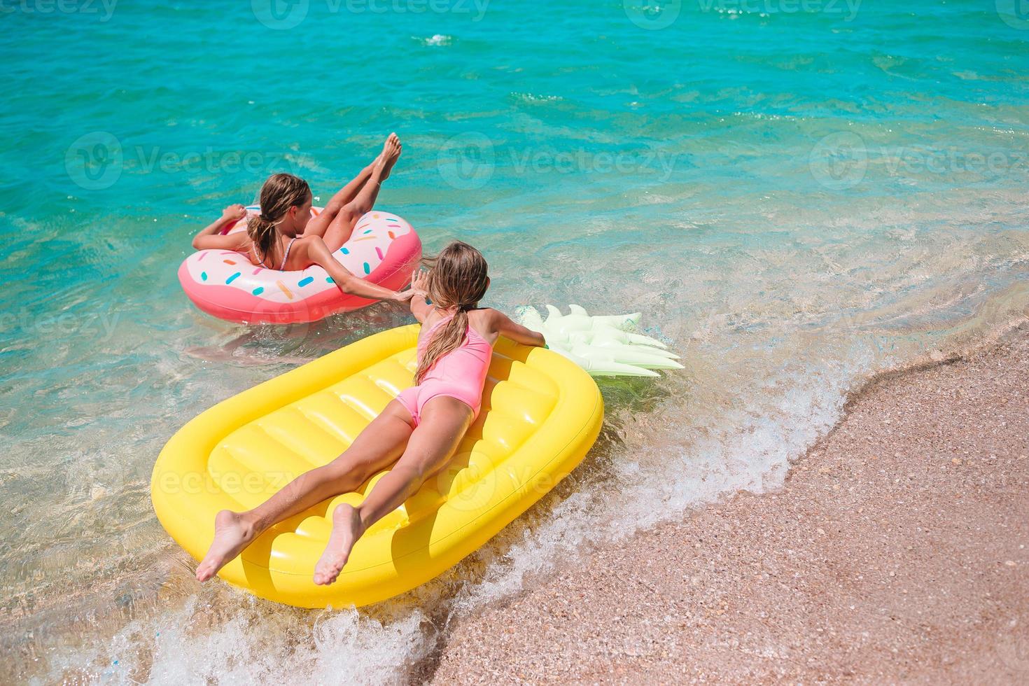 Little girls having fun at tropical beach during summer vacation playing together photo