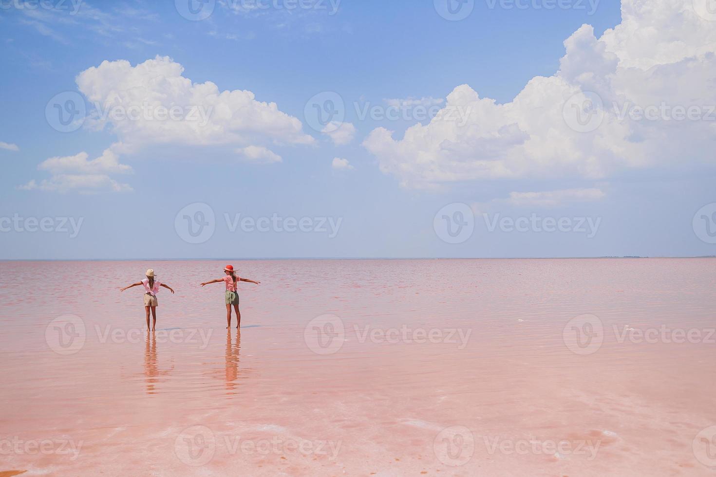 Girls on a pink salt lake on a sunny summer day. photo