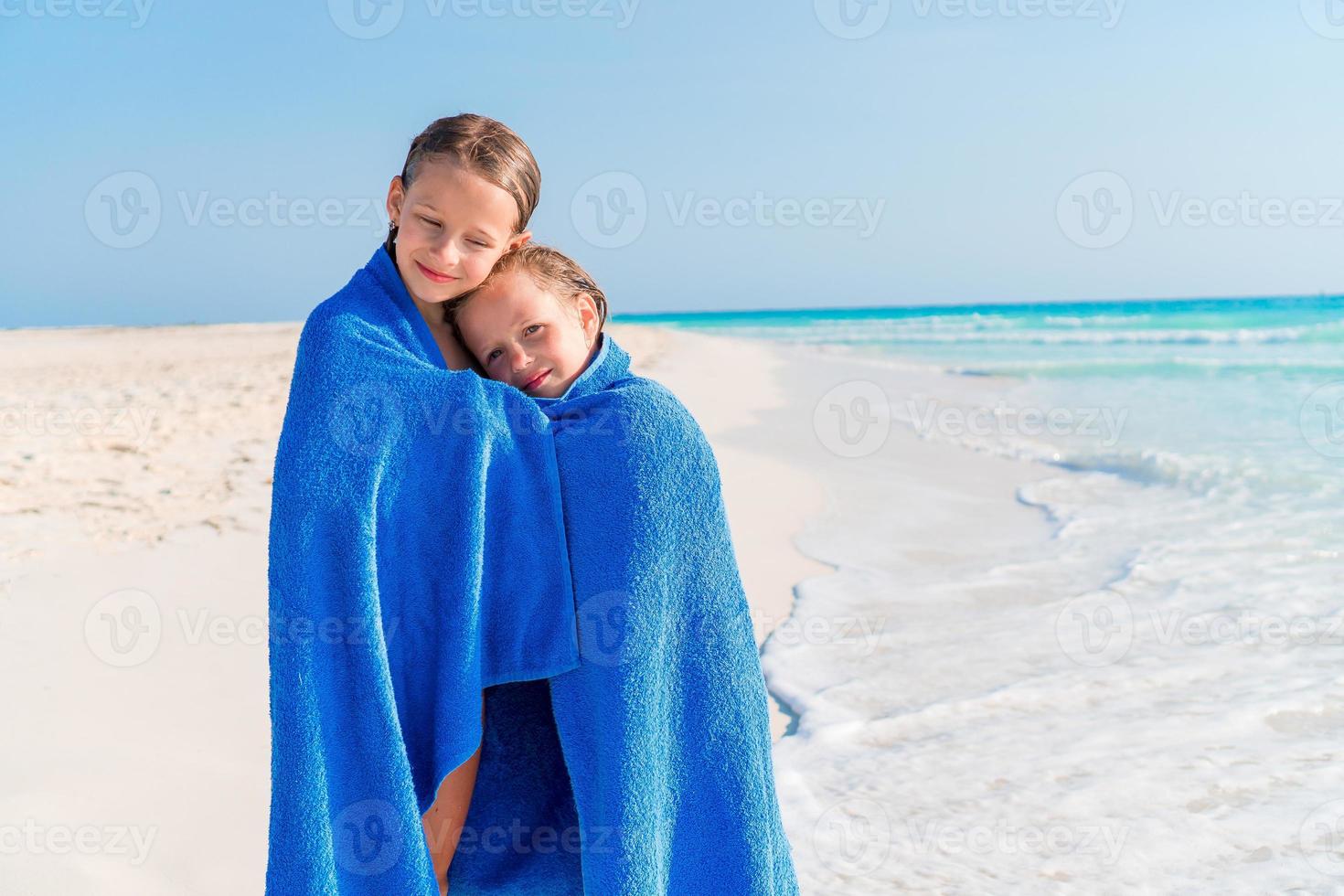 Little girls having fun running with towel and enjoying vacation on tropical beach photo