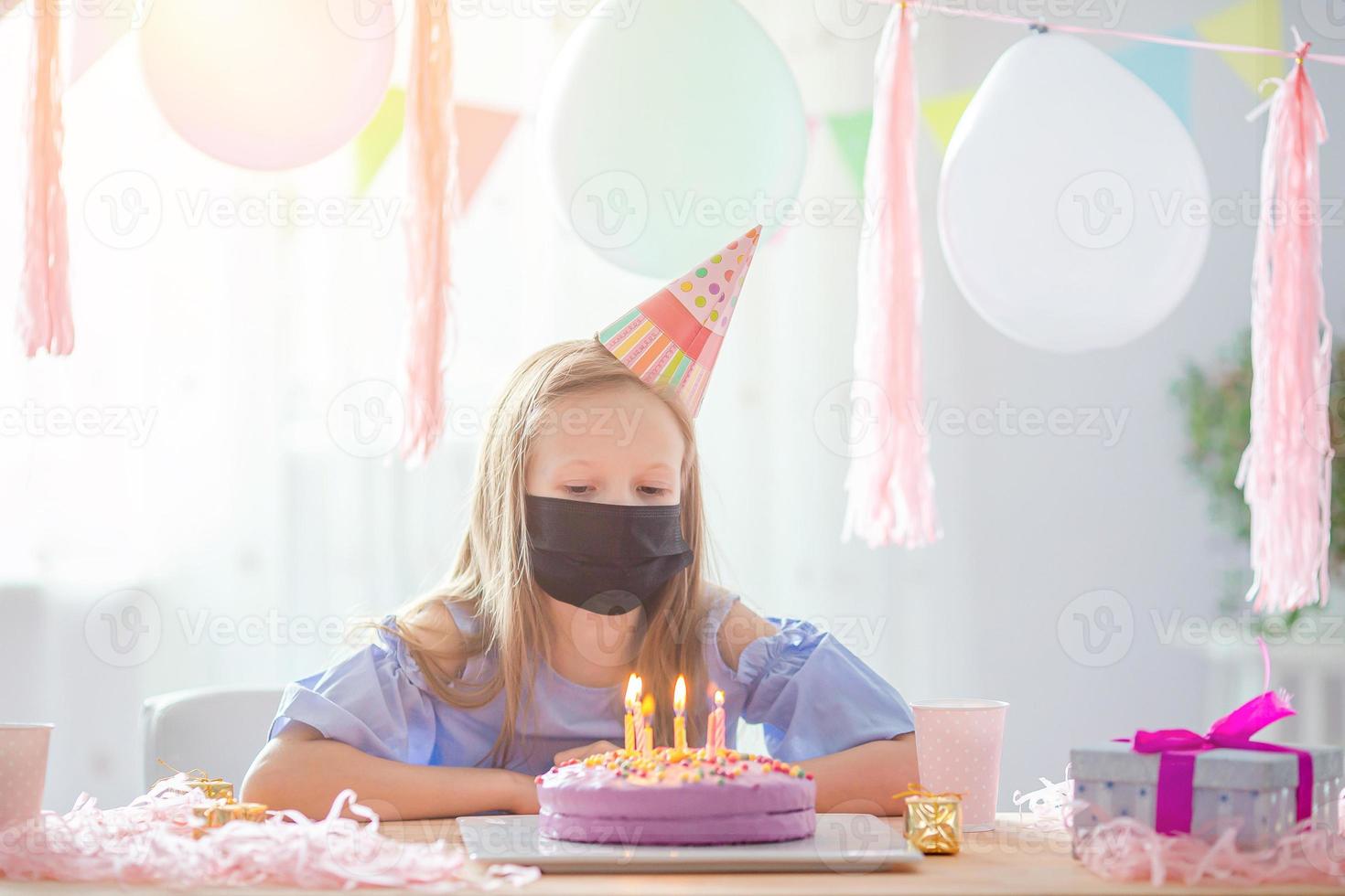 niña caucásica usa una máscara en su cumpleaños. fondo colorido festivo con globos. concepto de fiesta y deseos de cumpleaños. foto