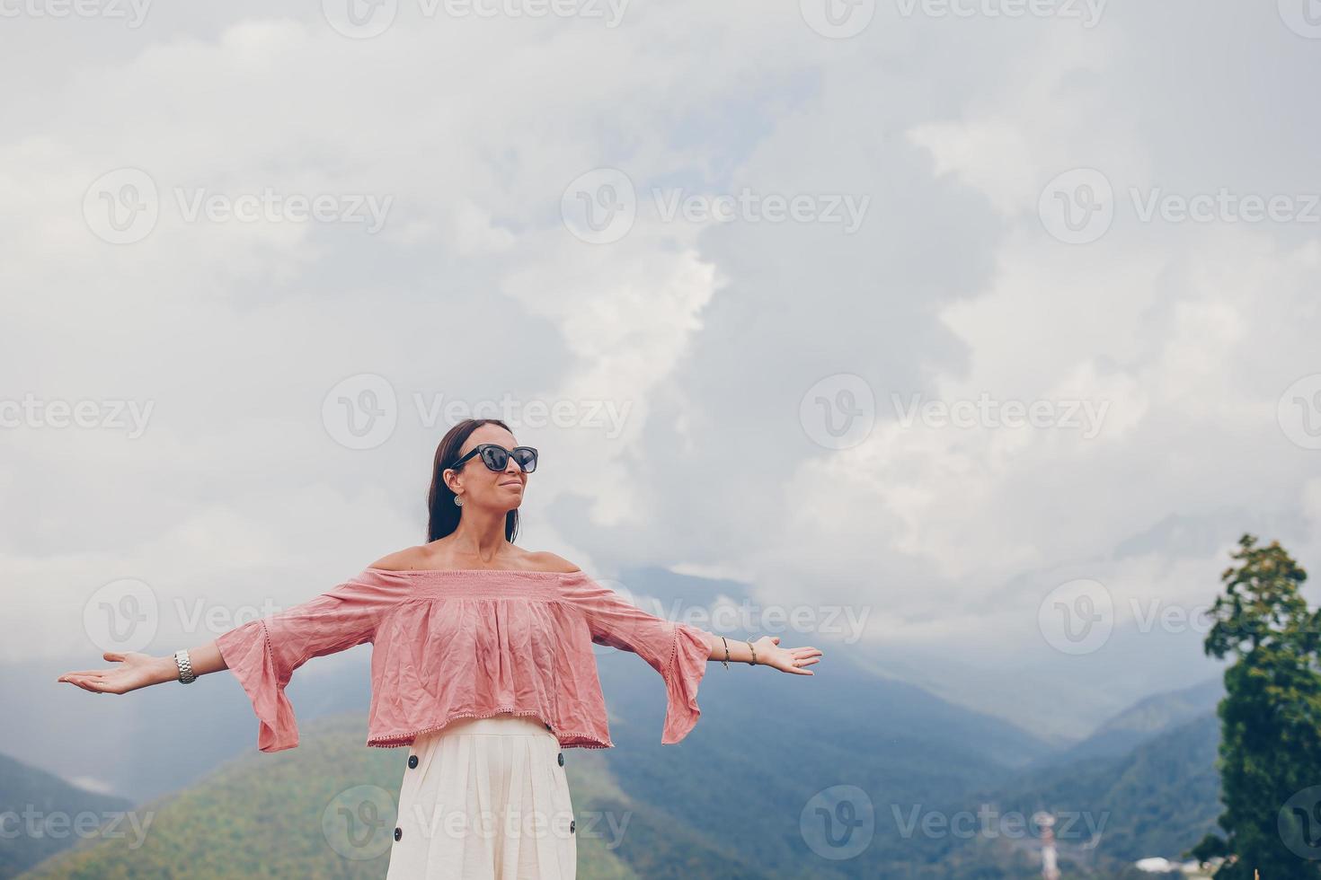 Beautiful happy young woman in mountains in the background of fog photo