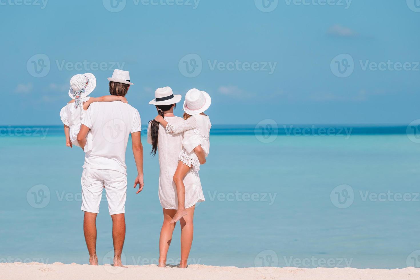Happy family of four on white beach photo