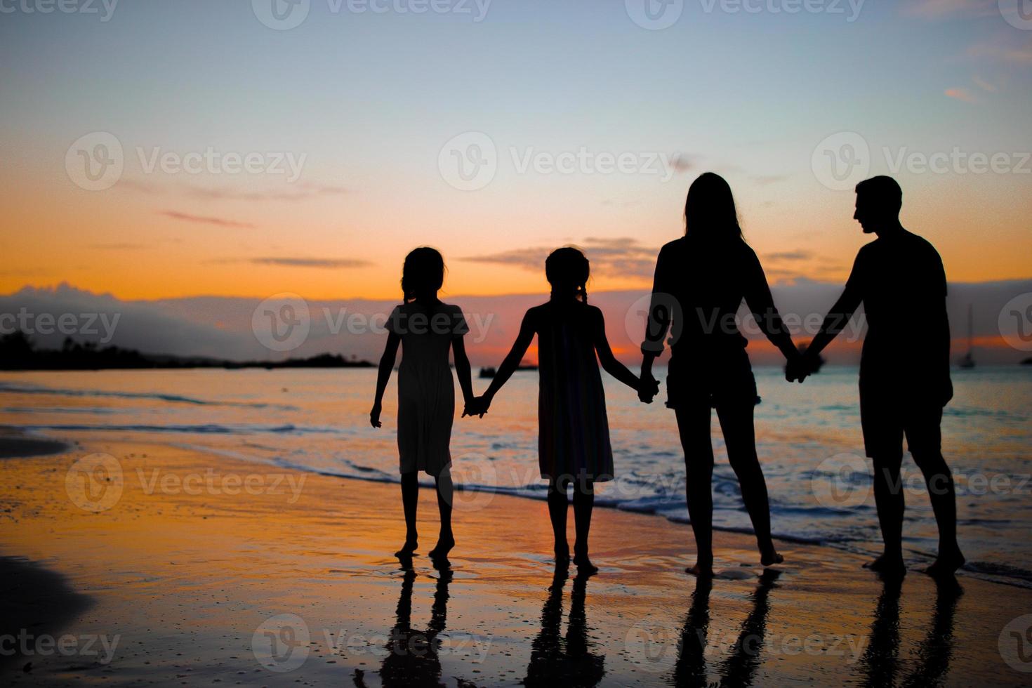 Family silhouette in the sunset at the beach photo