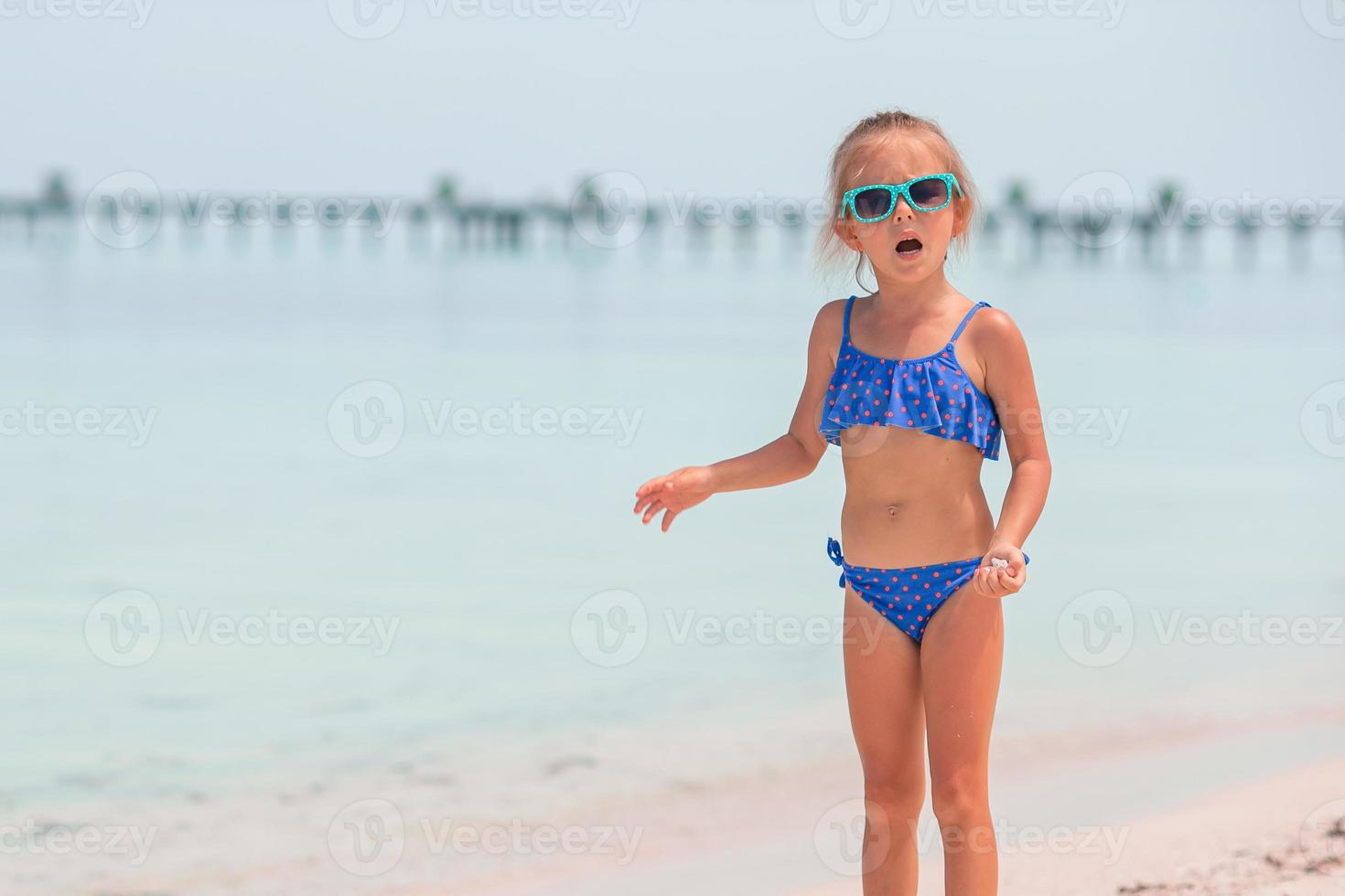 Beautiful little girl in dress at beach having fun. Funny girl enjoy summer vacation. photo