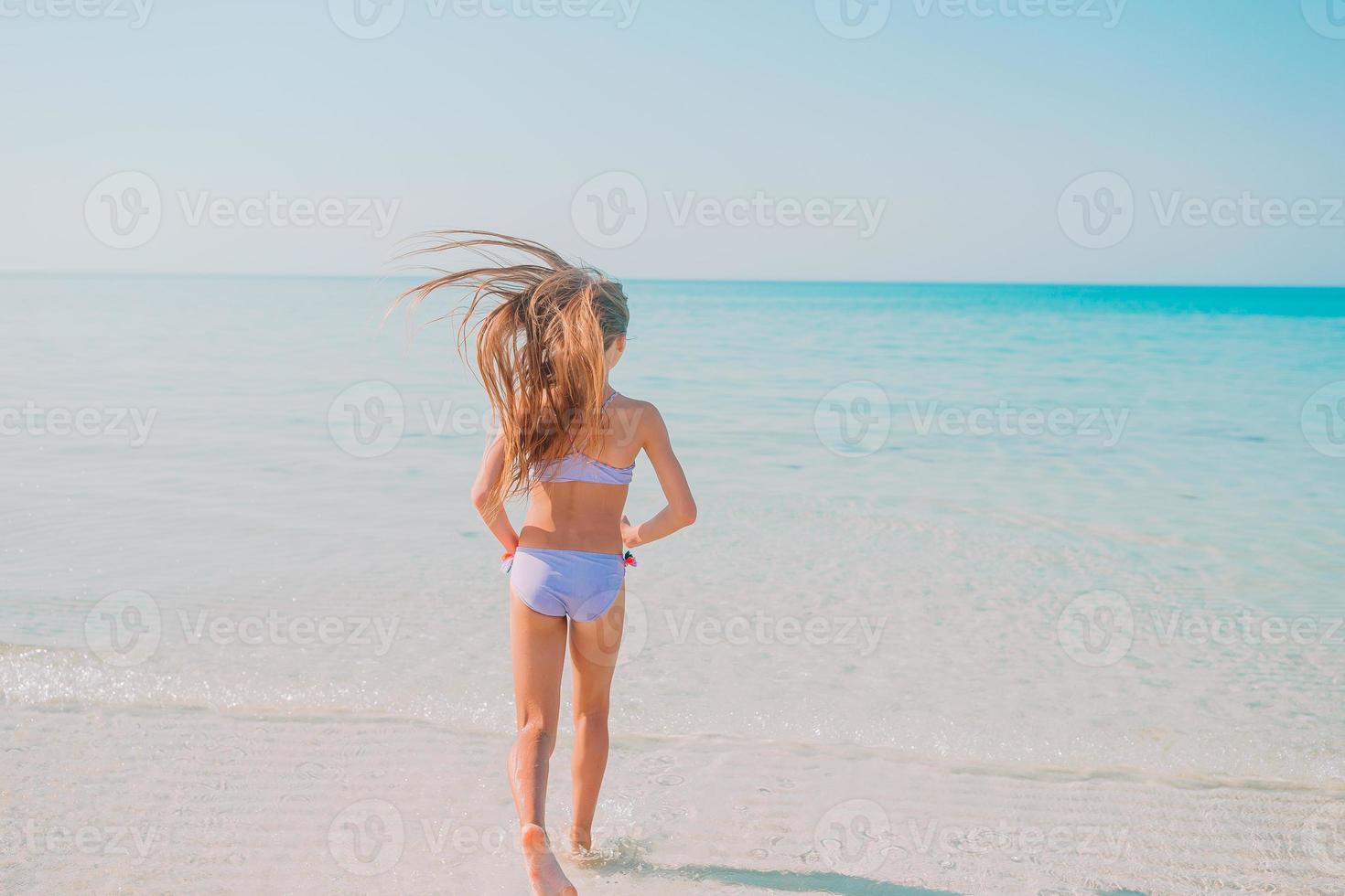 Adorable active little girl at beach during summer vacation photo