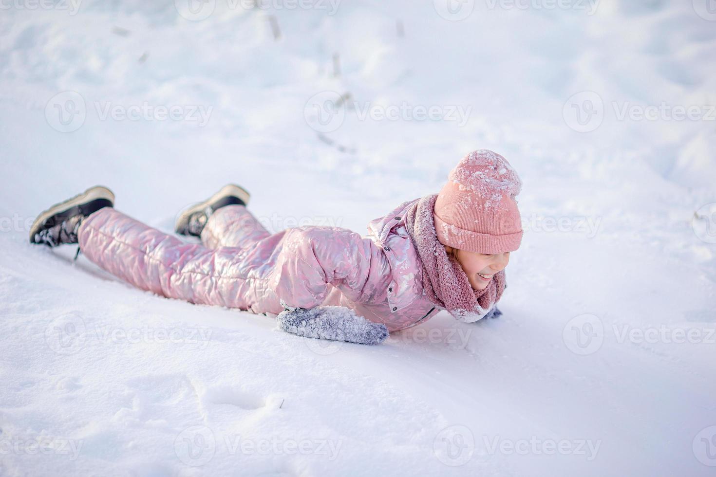 Adorable little happy girl sledding in winter snowy day. photo