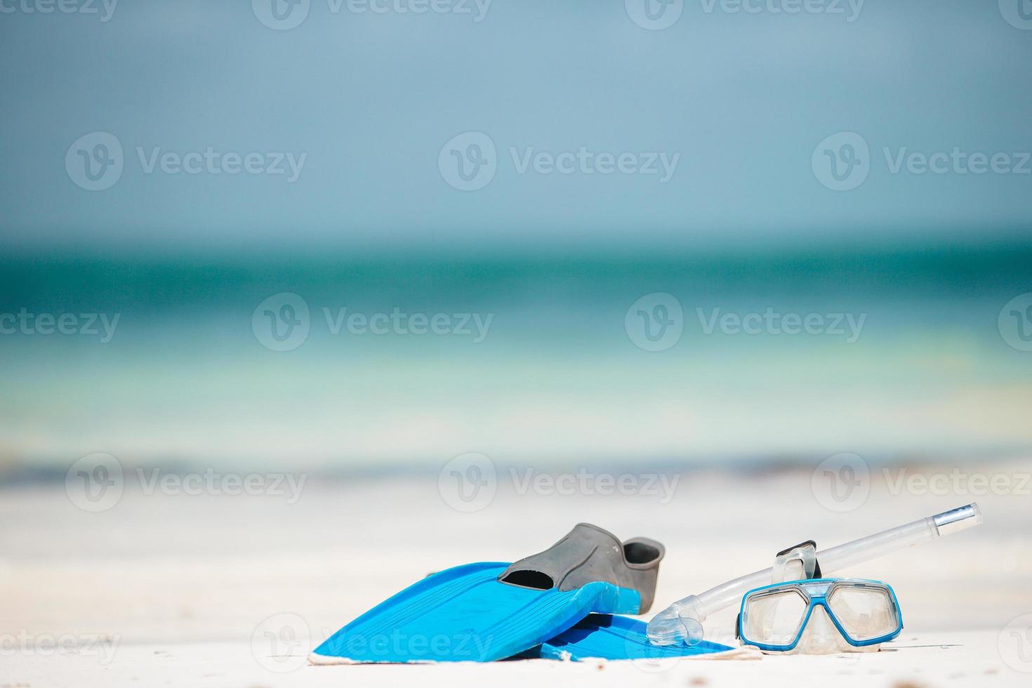 Snorkeling equipment mask, snorkel and fins on white beach photo