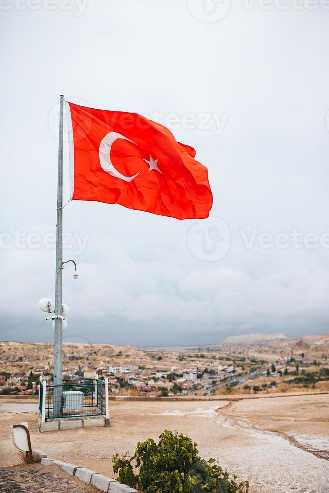 Turkish national flag with background of Goreme town, in Goreme national park. Cappadocia, Turkey photo