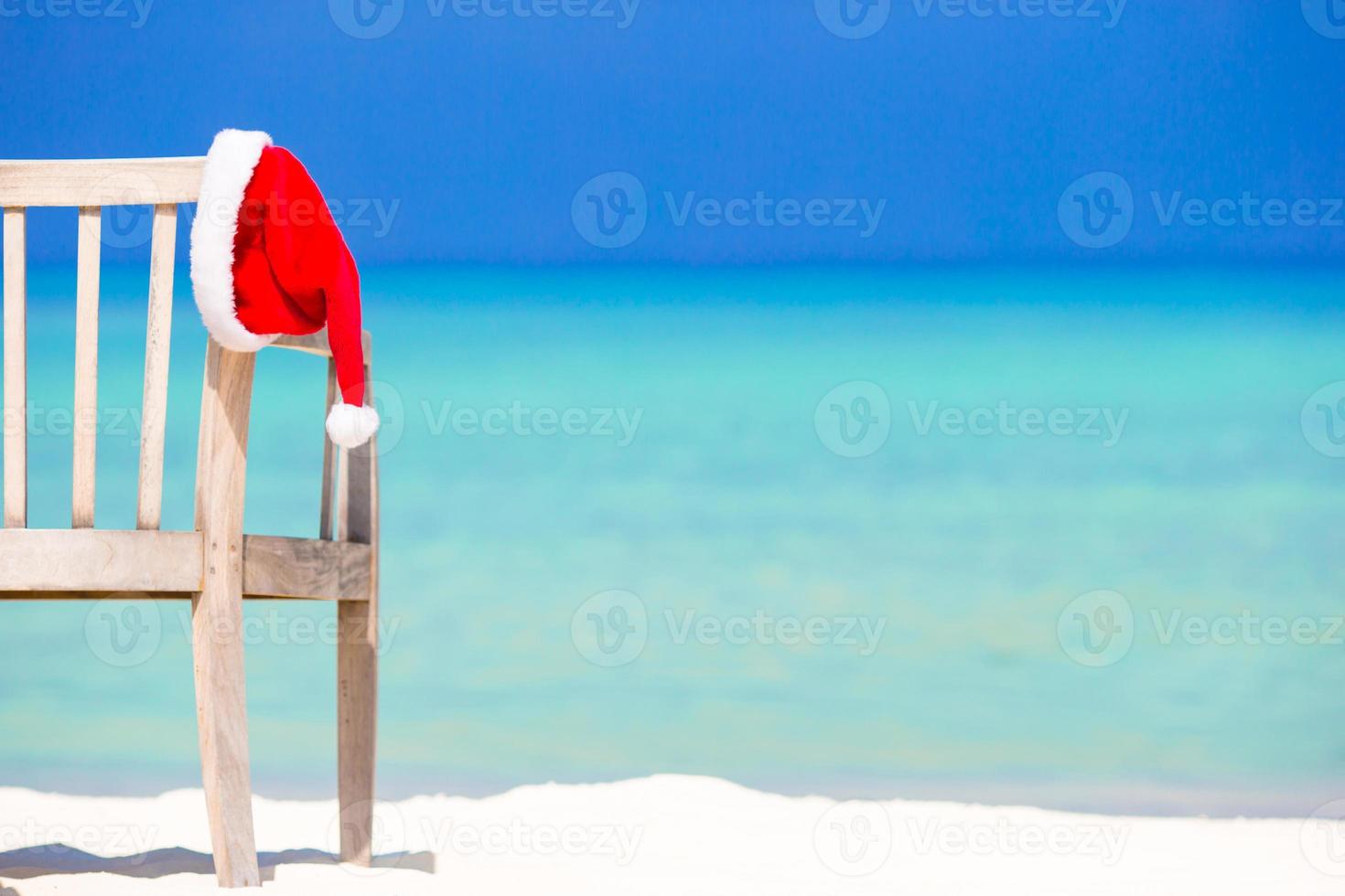 Red santa hat on beach chair at tropical vacation photo