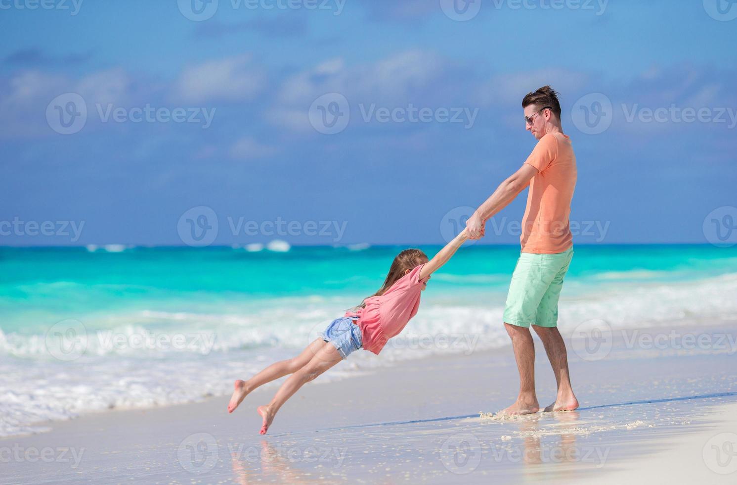 Little girl and happy dad having fun during beach vacation photo