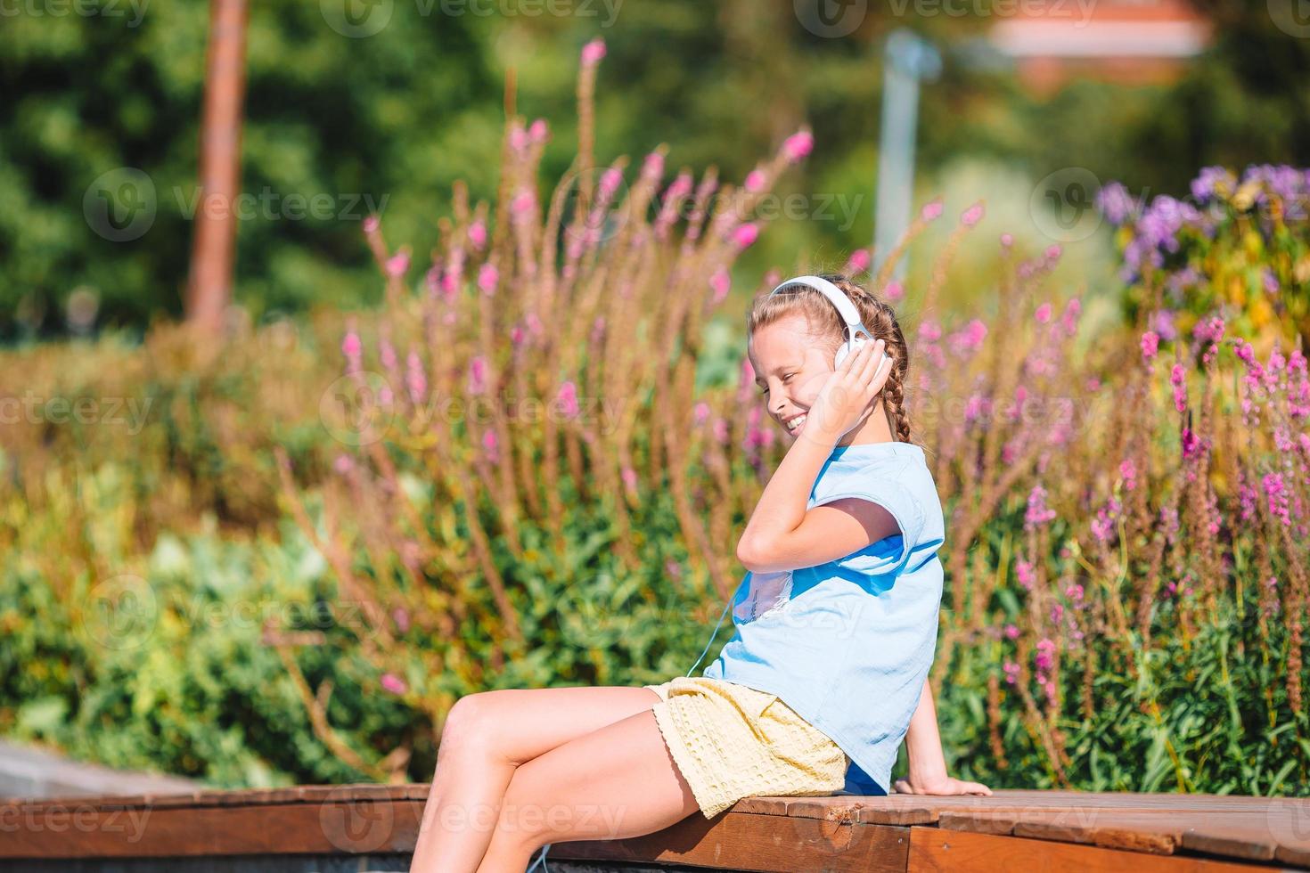 Little adorable girl listening music in the park photo