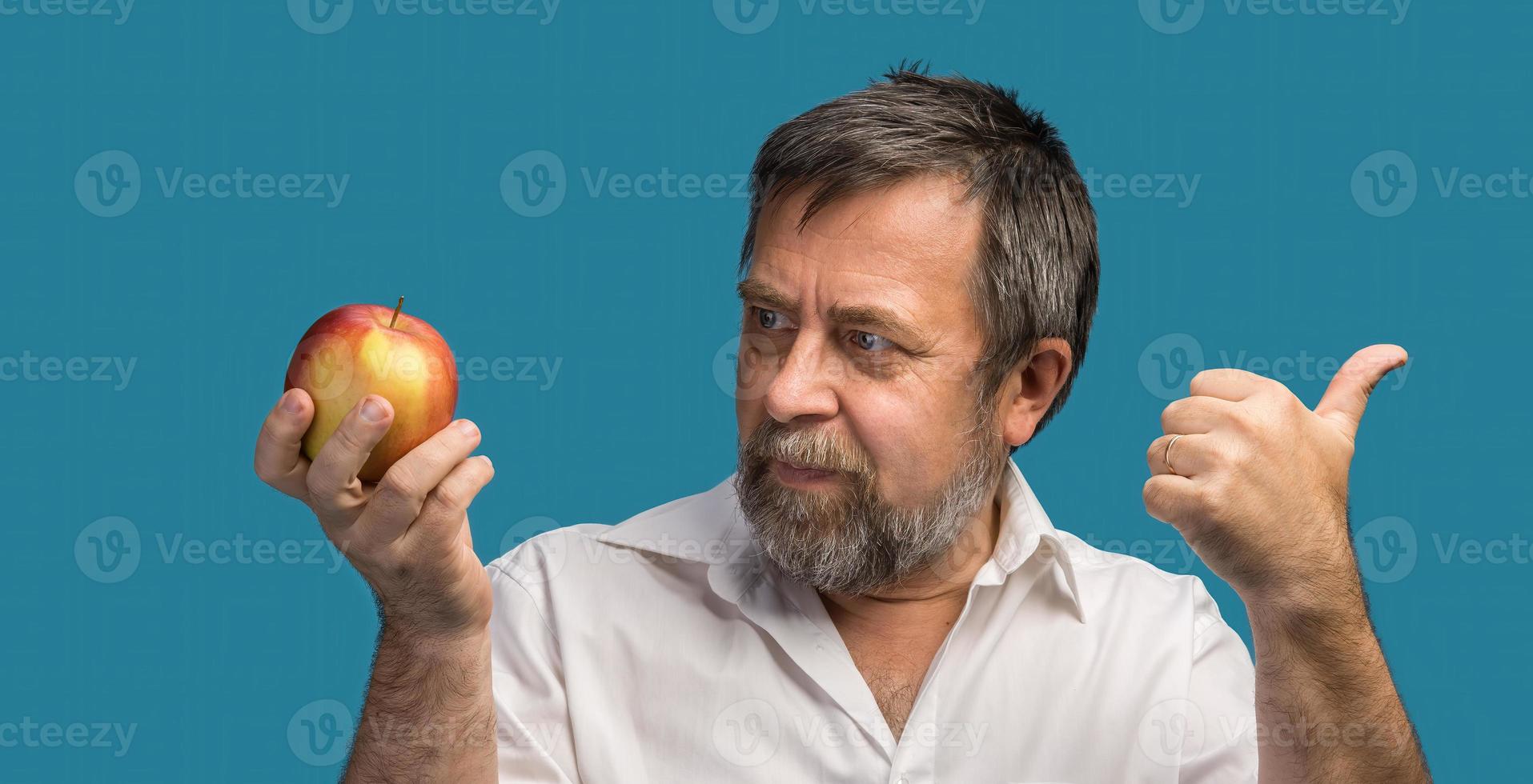 hombre de mediana edad sosteniendo una manzana roja foto