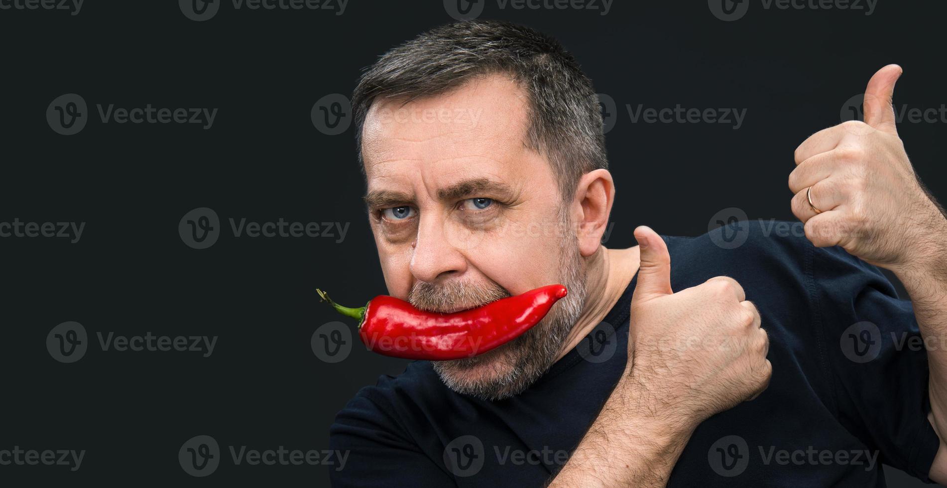 elderly man with red pepper in his mouth photo