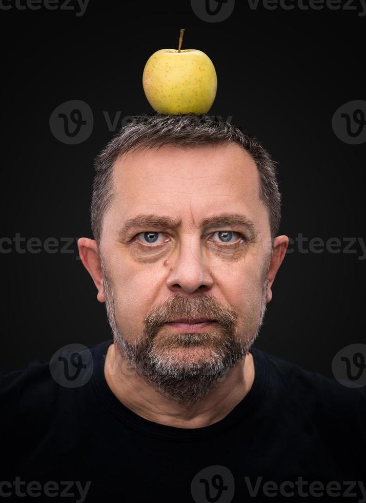 hombre con una manzana verde en la cabeza foto