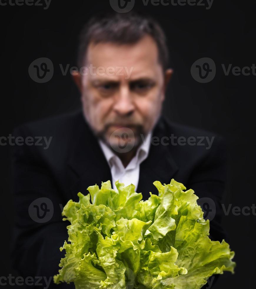 hombre sosteniendo y comiendo lechuga foto