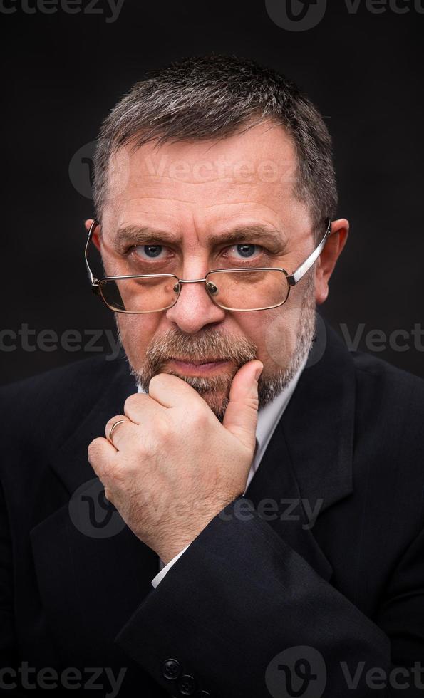 senior man with glasses prop up the head with his hand photo