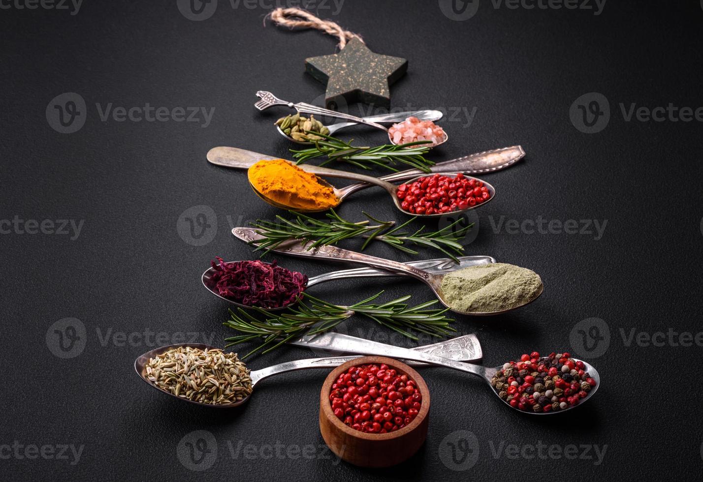 Composition consisting of a variation of spices in metal spoons laid out in the shape of a Christmas tree photo