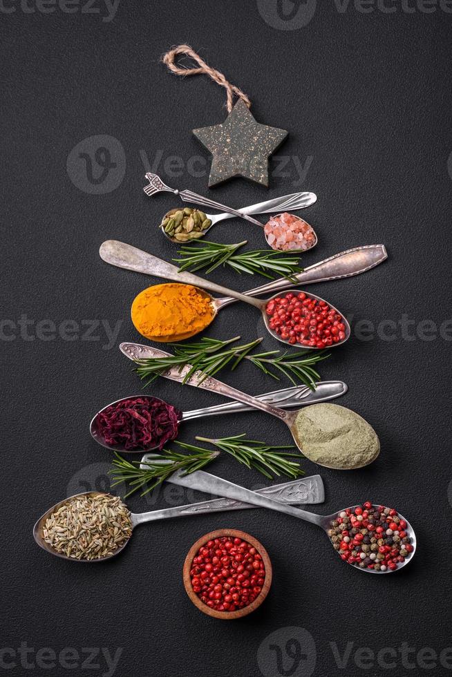 Composition consisting of a variation of spices in metal spoons laid out in the shape of a Christmas tree photo