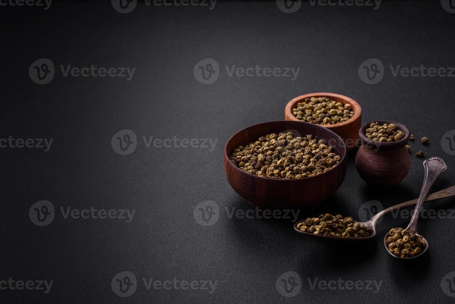 Spice, allspice green in a wooden bowl on a black concrete background photo