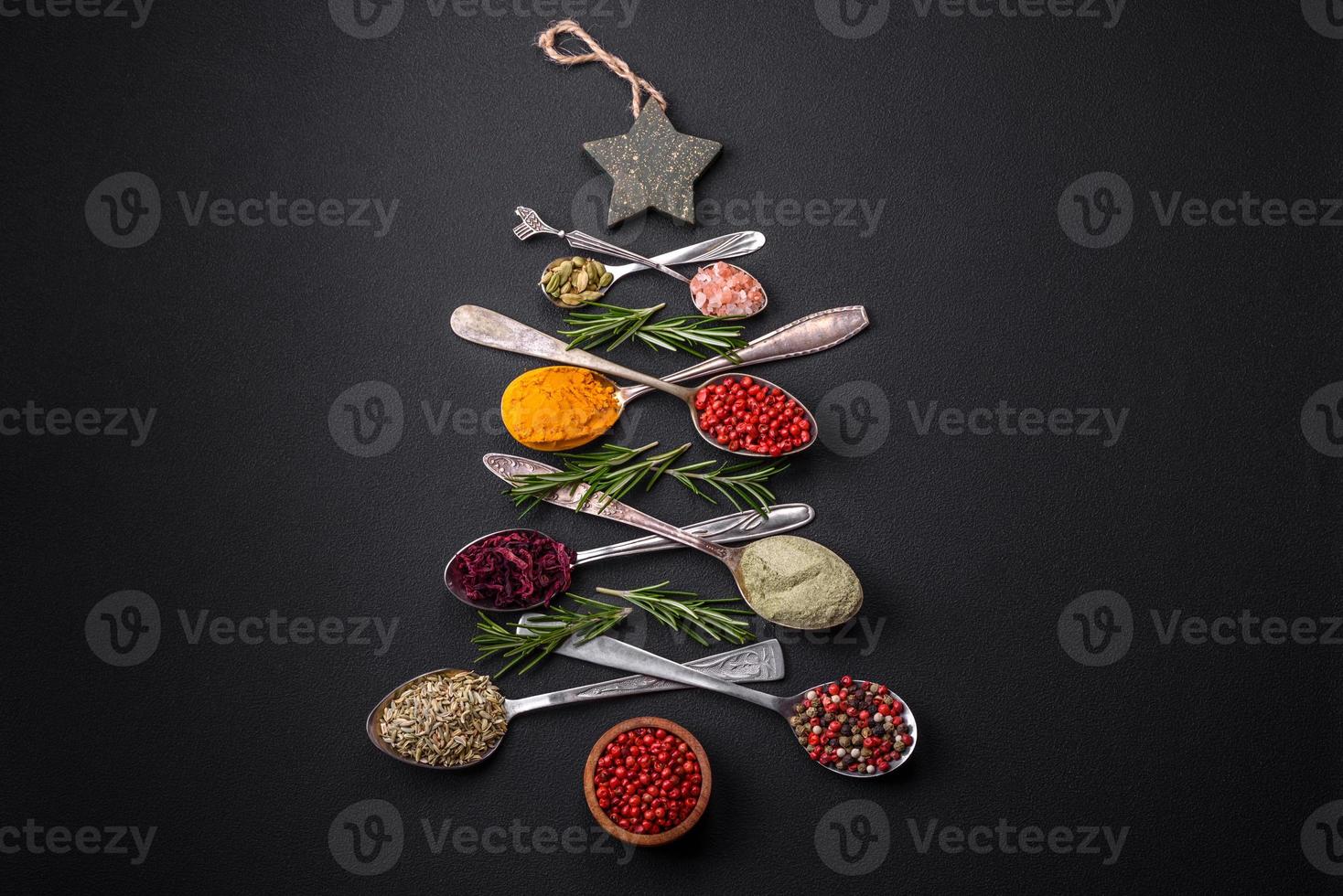 Composition consisting of a variation of spices in metal spoons laid out in the shape of a Christmas tree photo