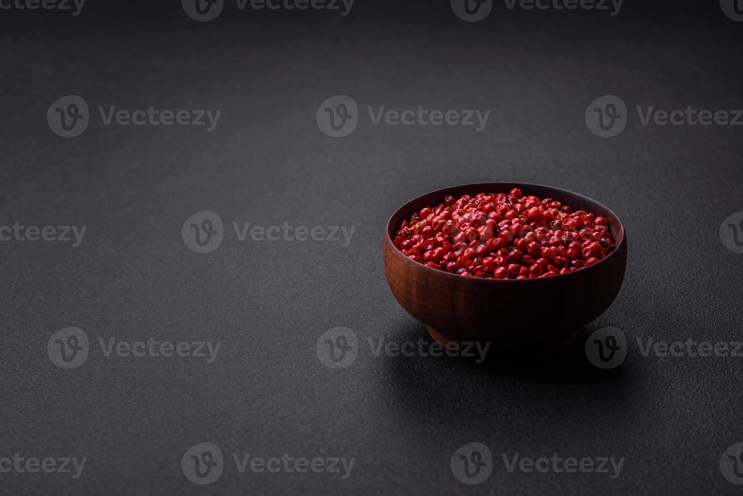 Spice, allspice peas of red or pink color in a wooden bowl photo