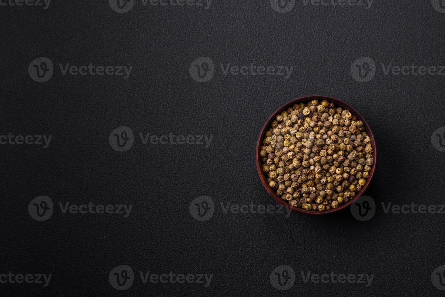 Spice, allspice green in a wooden bowl on a black concrete background photo