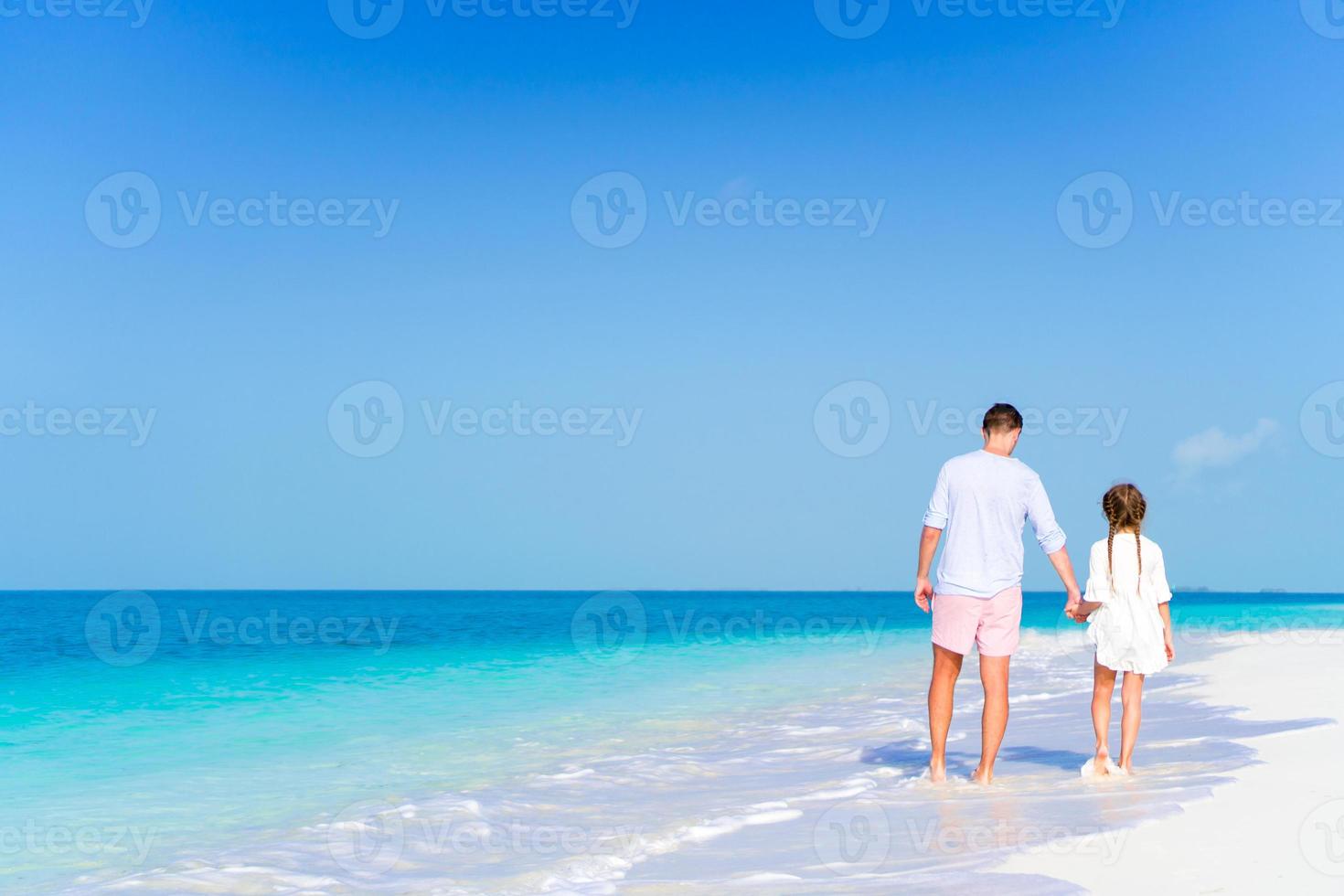 papá feliz y niña disfrutando de la playa caminando por la orilla del mar foto