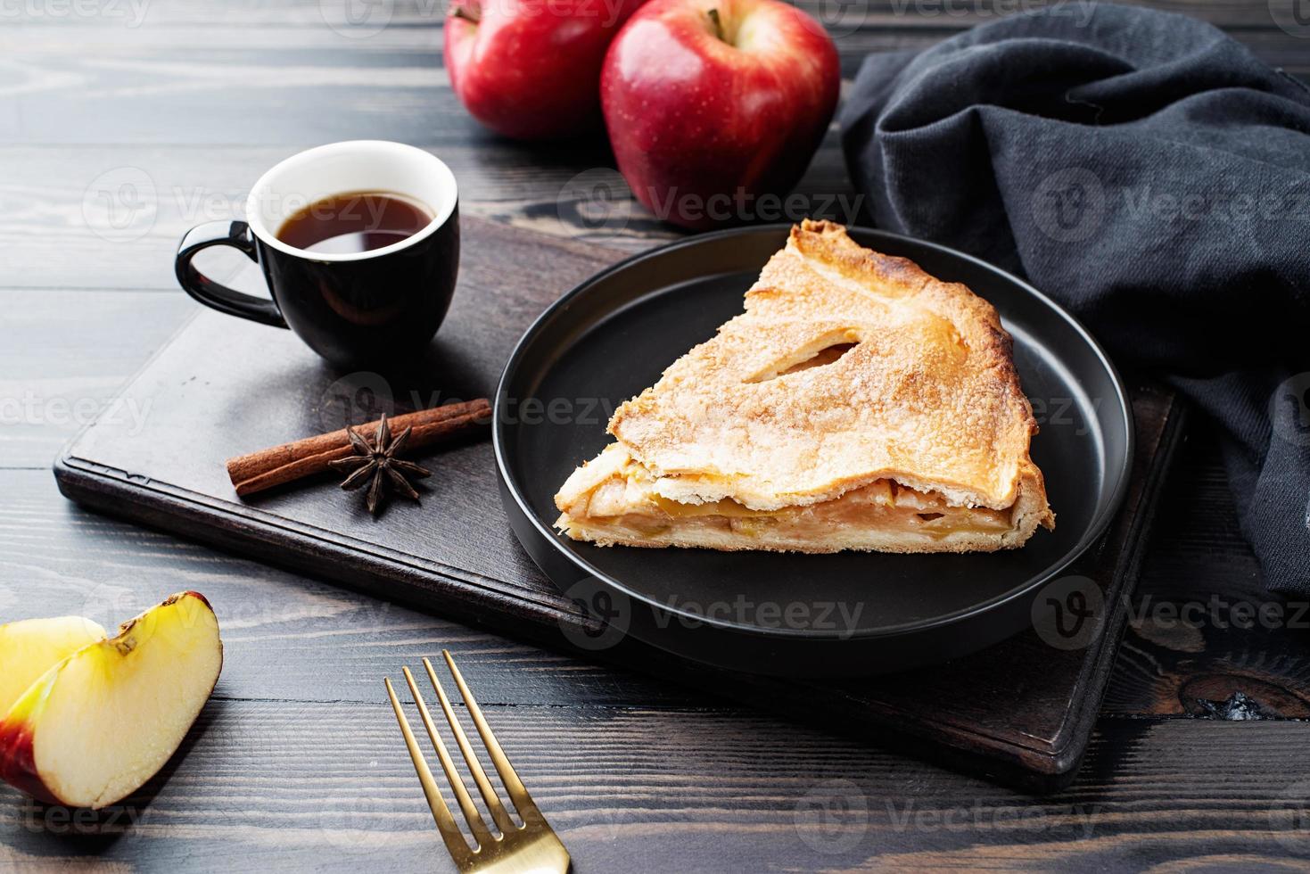 Homemade piece of apple pie with fresh red apples on black table photo