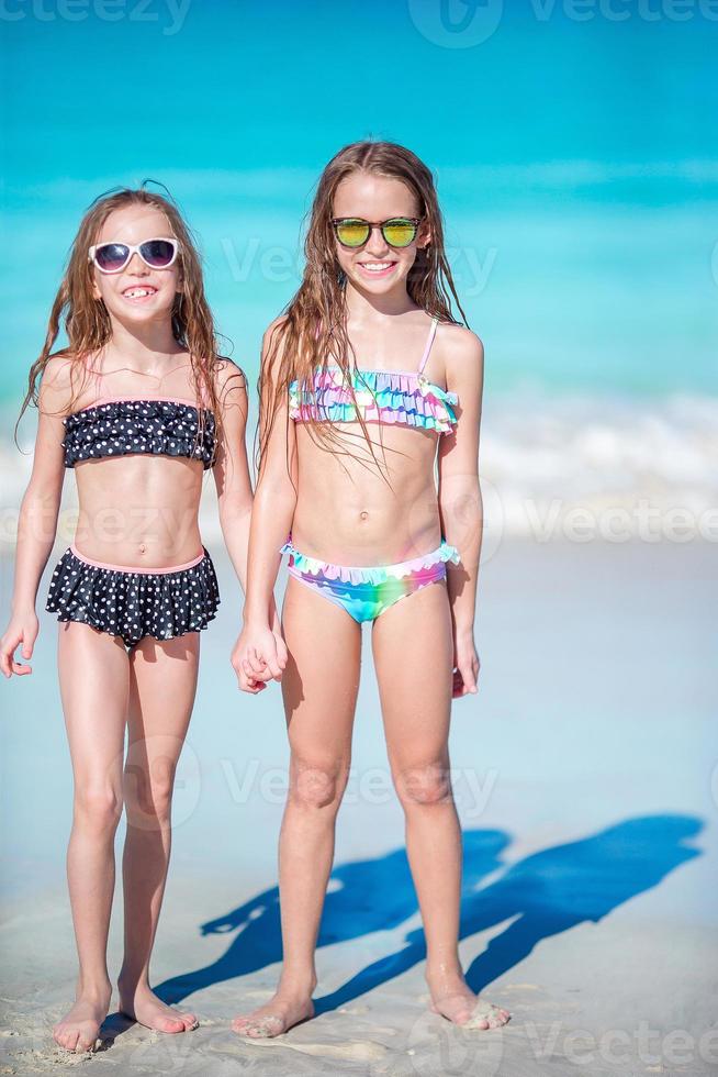 Adorable little girls have a lot of fun on the beach. Two beautiful kids are happy photo