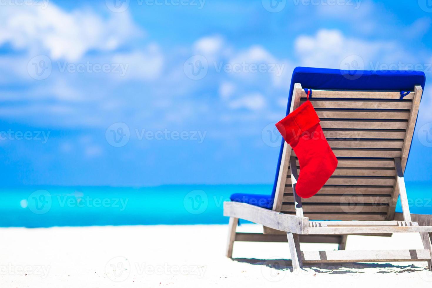 Red Christmas stocking on chair longue at tropical white beach photo