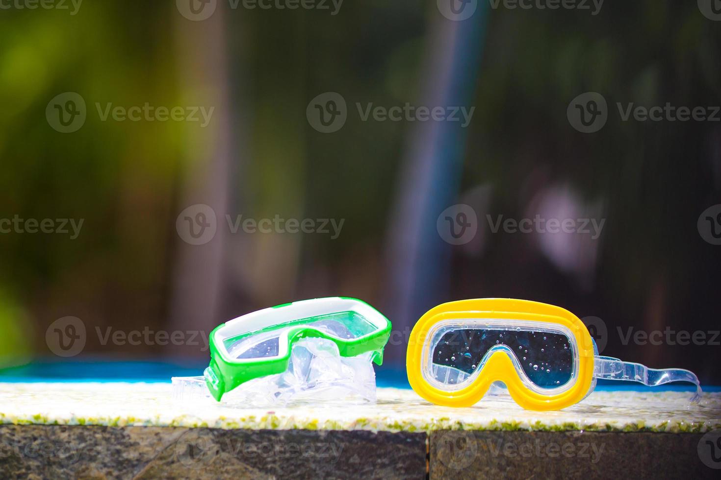 Two wet scuba masks lying near swimming pool photo