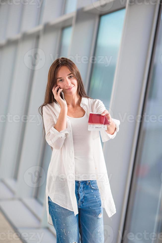 Woman tourist talking by cell phone with boarding passport at airport photo