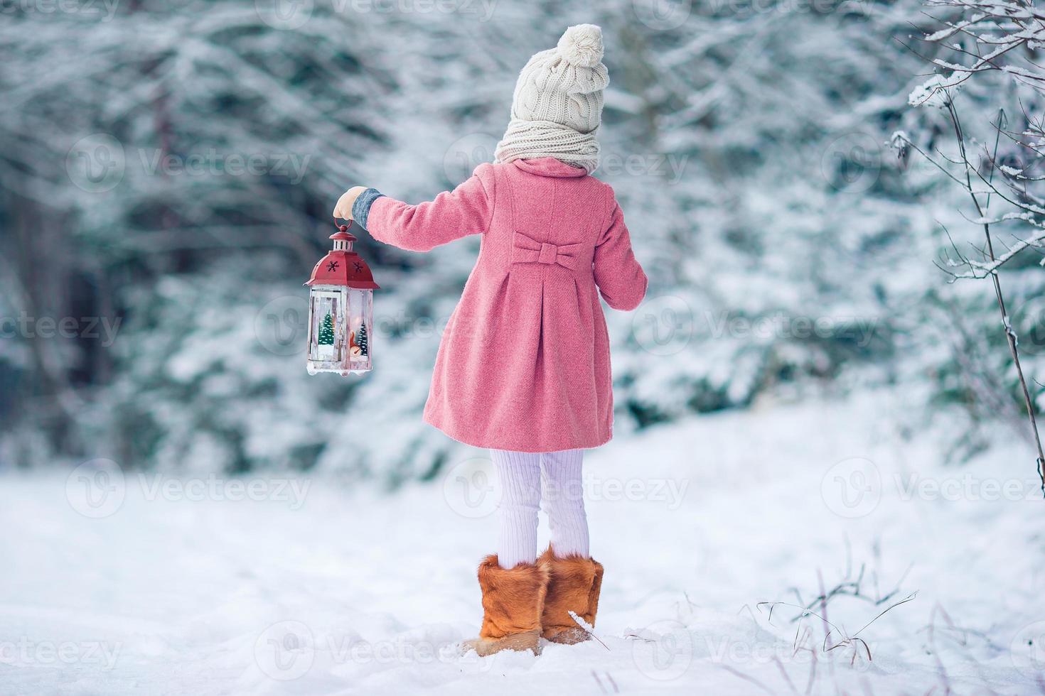 Adorable little girl with flashlight and candle in winter photo