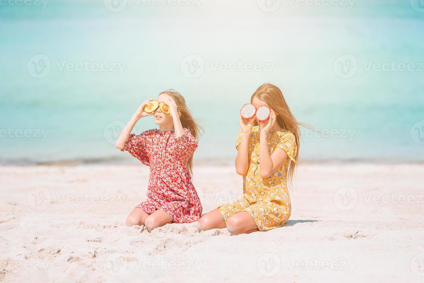 Little happy funny girls have a lot of fun at tropical beach playing together. photo