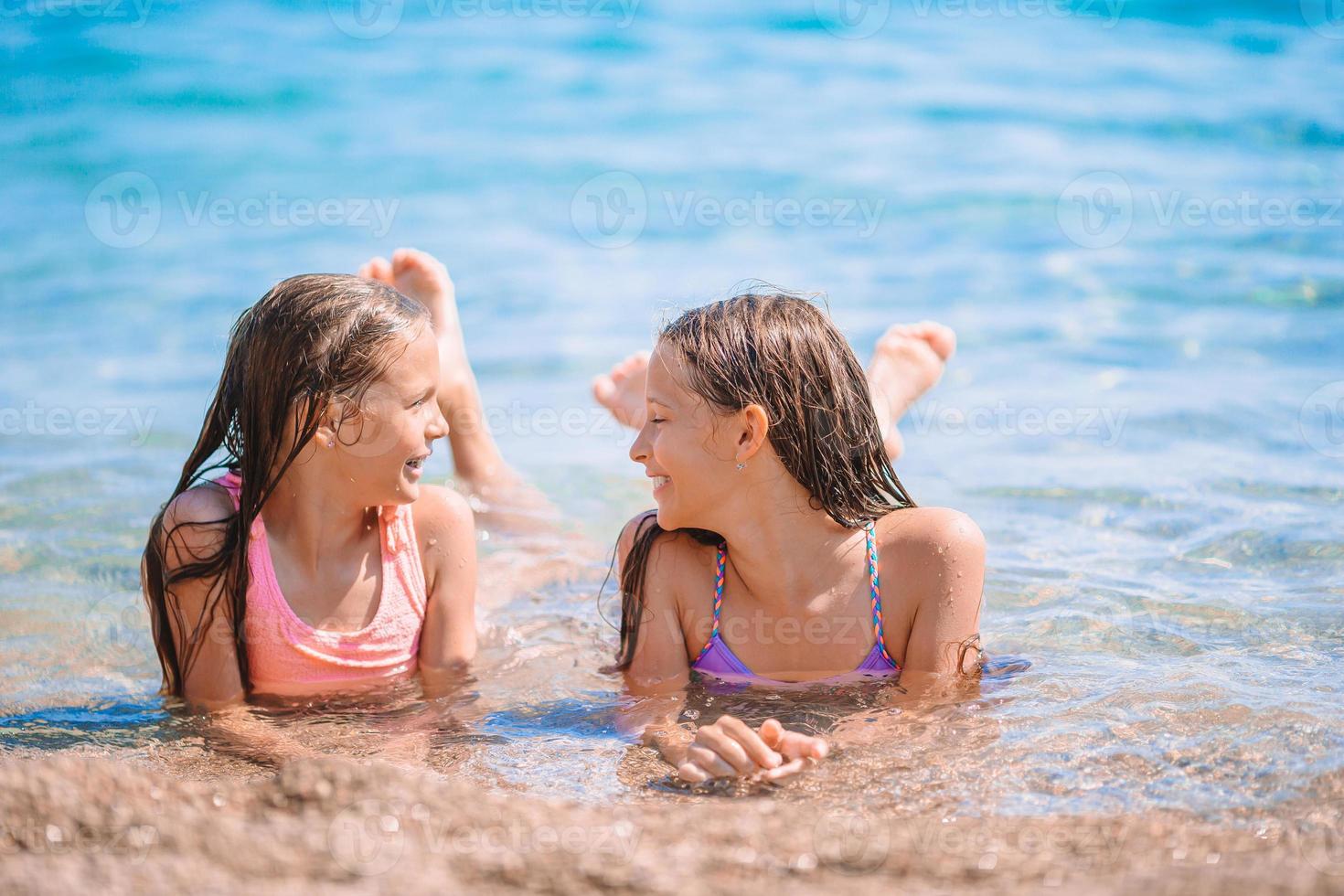 Adorable little girls having fun on the beach photo