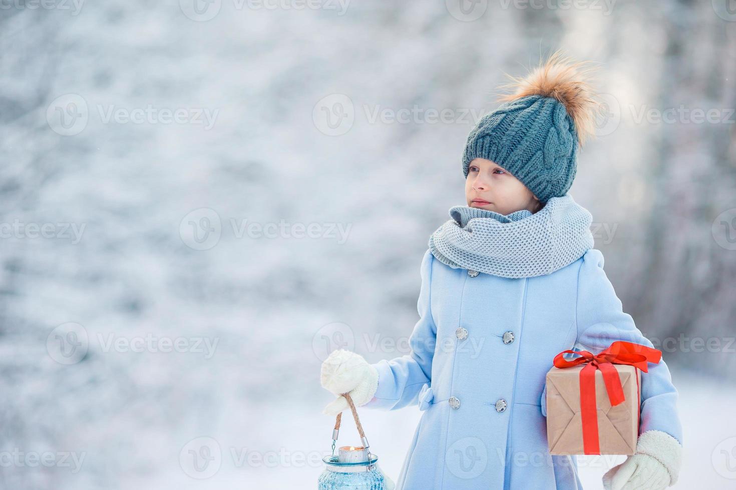 Adorable girl with christmas box gift in winter outdoors photo