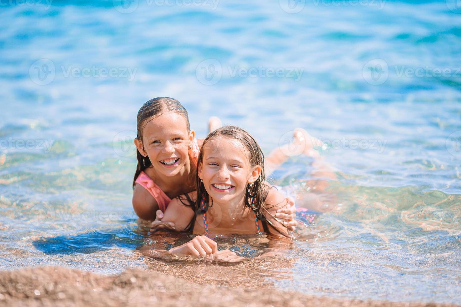 Adorable little girls having fun on the beach photo