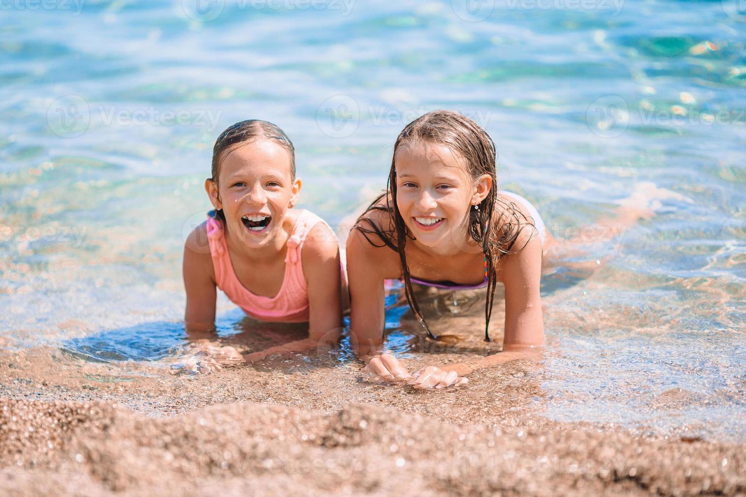 Adorable little girls having fun on the beach photo