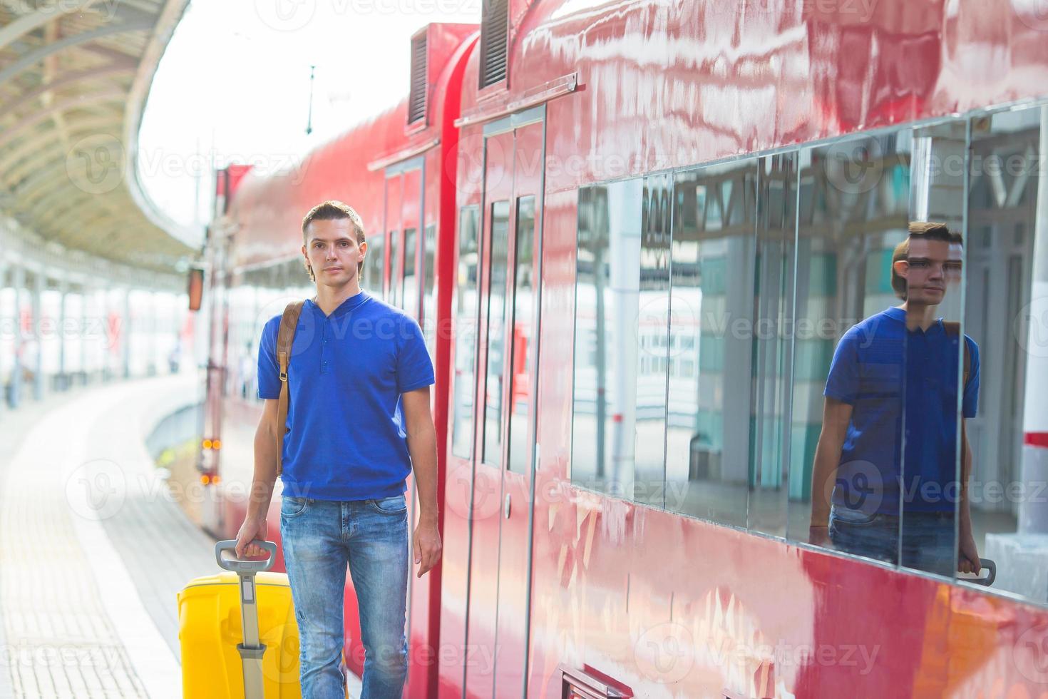 joven caucásico con equipaje en la estación viajando en tren foto