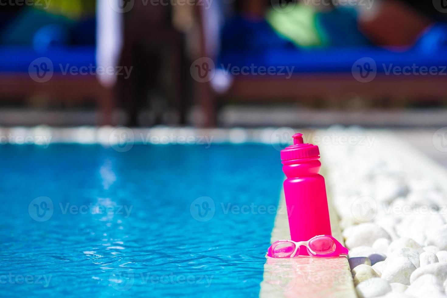 Pink sporty water bottle near swimming pool photo