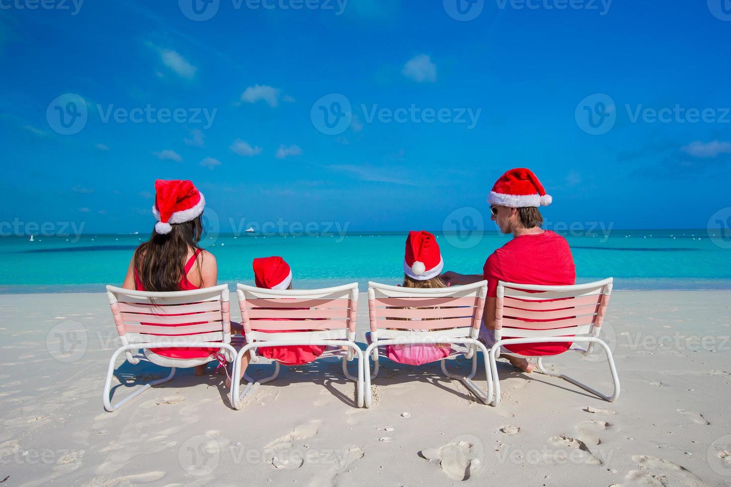 Happy family of four in Christmas Hats during tropical vacation photo