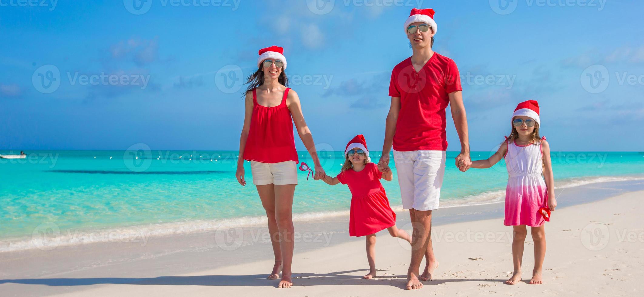 Happy family of four in Christmas Hats during tropical vacation photo