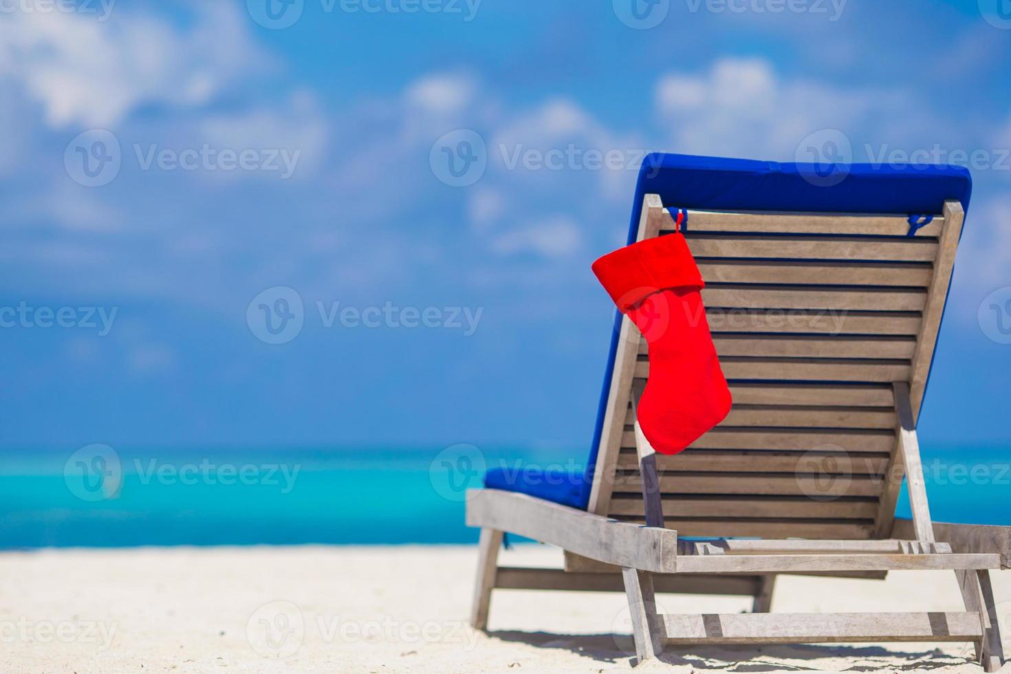 Red Christmas stocking on chair longue at tropical white beach photo