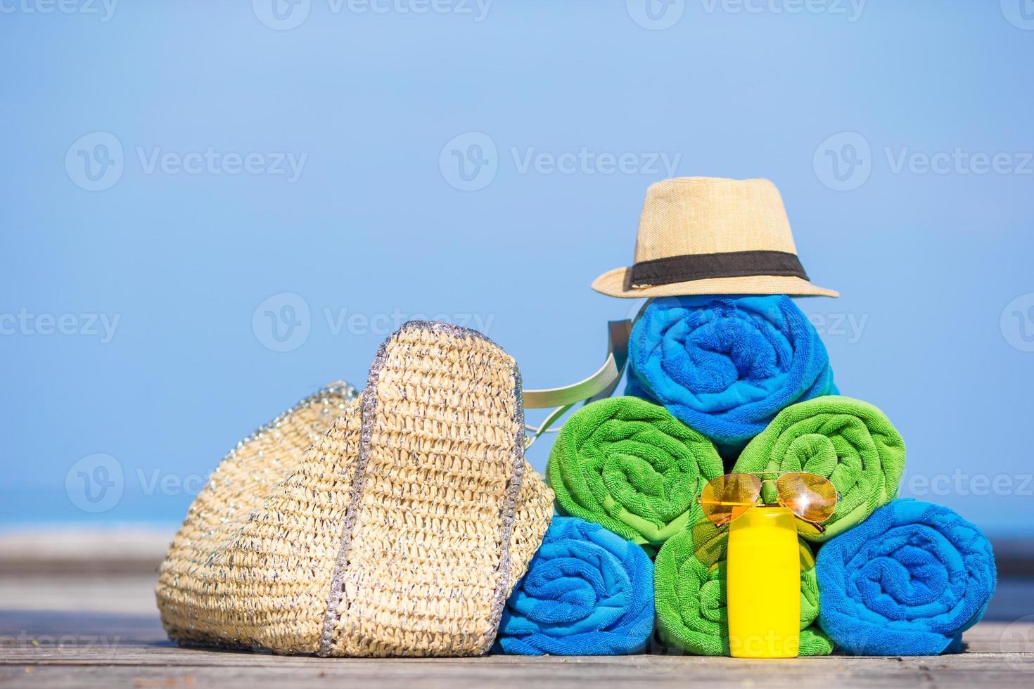 Beach and summer vacation accessories concept - close-up of colorful towels, hat, bag and sunblock photo