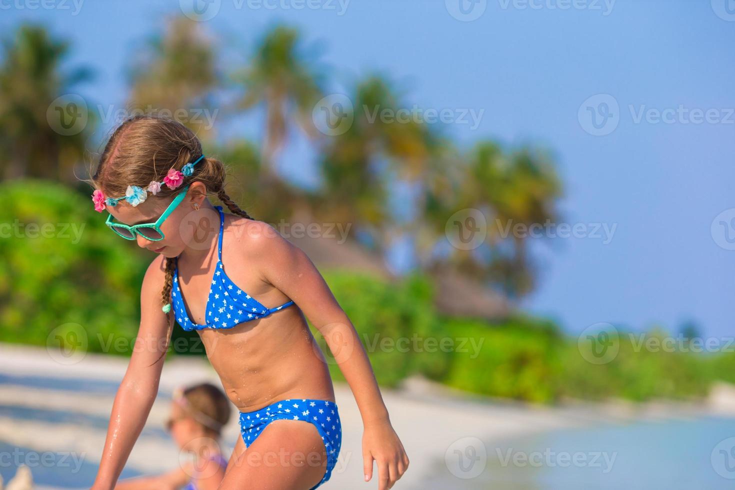 Adorable little girls playing with beach toys during tropical vacation photo